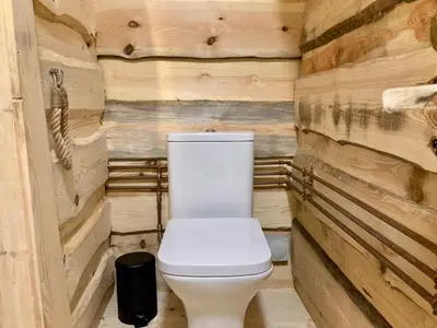 a toilet in a room with wooden walls at The Prancing Moose in Ystrad Meurig