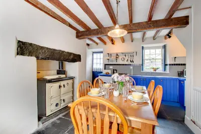 a kitchen with blue cabinets and a wooden table and chairs at 2 Bed in Dolgellau oc-wah671 in Dolgellau