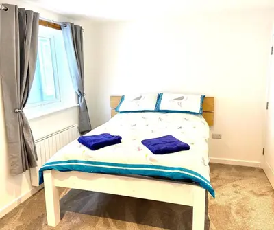 a bedroom with a bed with blue sheets and a window at Harbour Lights Apartment New Quay in New Quay