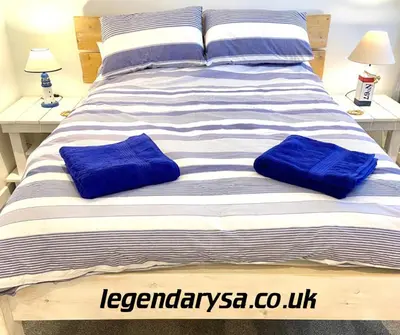 a large bed with two blue pillows on it at Harbour Lights Apartment New Quay in New Quay