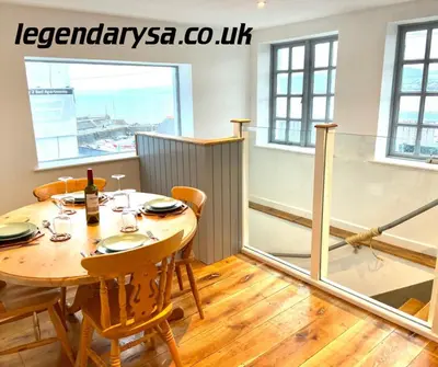 a dining room with a table and chairs and a window at Harbour Lights Apartment New Quay in New Quay