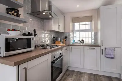 a kitchen with white cabinets and a microwave at Seagrass Cottage - Aberdovey in Aberdyfi
