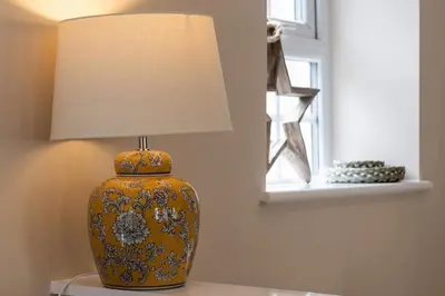 a yellow vase sitting on a table with a lamp at Seagrass Cottage - Aberdovey in Aberdyfi