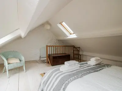 a attic room with a bed and a chair at 1 Hetfield Cottages in Bishops Castle