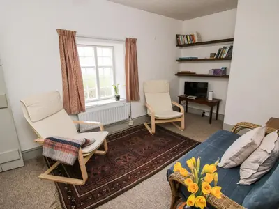 a living room with two chairs and a bed and a window at 1 Hetfield Cottages in Bishops Castle