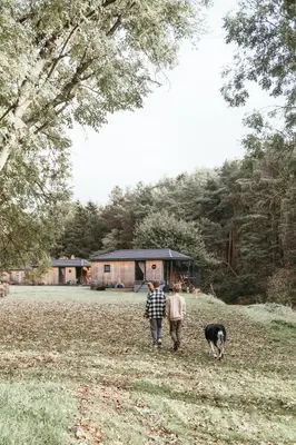 two people and a dog walking in a field at Riverside Cabins in Shrewsbury