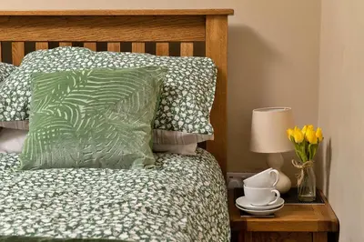 a bed with a green pillow and flowers on a night stand at Finest Retreats - Felin Ship in Dolgellau