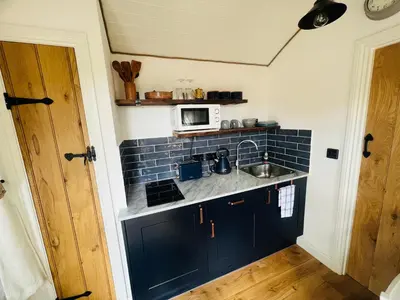 a kitchen with a sink and a microwave at Romantic Shepherds Hut with Hot Tub in The Heart of Snowdonia in Dolgellau