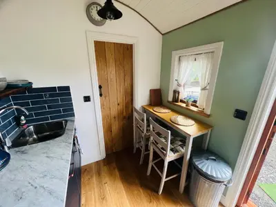 a small kitchen with a table and a window at Romantic Shepherds Hut with Hot Tub in The Heart of Snowdonia in Dolgellau