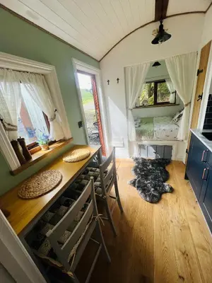 a room with a table and a bed in a room at Romantic Shepherds Hut with Hot Tub in The Heart of Snowdonia in Dolgellau