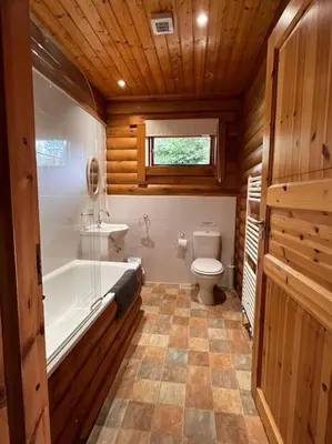 a bathroom with a toilet and a tub and a sink at Solid Log Cabin With Private Hot Tub - Oak in Aymestrey