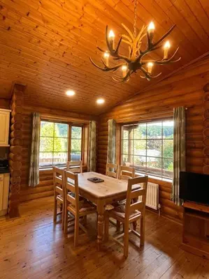 a dining room with a table and chairs in a cabin at Solid Log Cabin With Private Hot Tub - Oak in Aymestrey