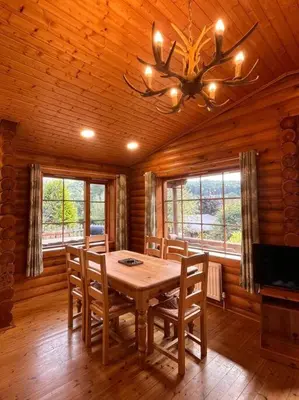 a dining room with a wooden table and chairs at Solid Log Cabin With Private Hot Tub - Oak in Aymestrey
