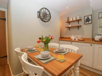 a kitchen and dining room with a wooden table and chairs at Pool Cottage in Hereford