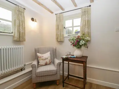 a living room with a chair and a table at Pool Cottage in Hereford