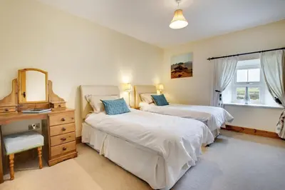 a bedroom with two beds and a dresser and a mirror at 5 Bed in Aberystwyth oc-wan443 in Llanychaiarn