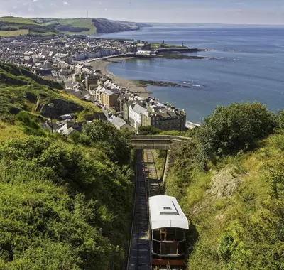 a train on a track with a city and the ocean at 5 Bed in Aberystwyth oc-wan443 in Llanychaiarn