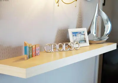 a shelf with a clock and books on it at Angorfa Aberaeron Apartment in Aberaeron