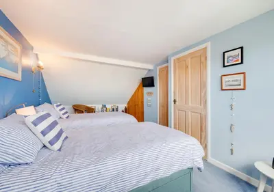 two beds in a bedroom with blue and white walls at Angorfa Aberaeron Apartment in Aberaeron