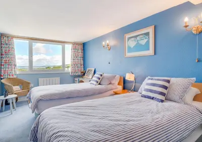 two beds in a room with blue walls at Angorfa Aberaeron Apartment in Aberaeron