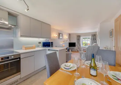 a kitchen and dining room with a table with wine glasses at Angorfa Aberaeron Apartment in Aberaeron