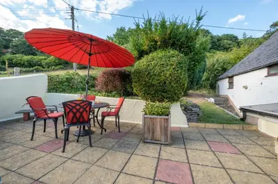 a table and chairs with a red umbrella on a patio at 2 Bed in Corwen oc-waf161 in Carrog