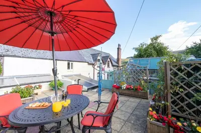 a patio with a table with a red umbrella at 2 Bed in Corwen oc-waf161 in Carrog