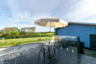 a table and chairs with an umbrella on a deck at 1 Bed in Aberystwyth oc-bow182 in Rhostie