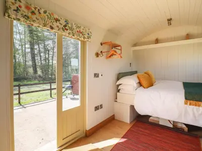 a bedroom with a bed and a sliding glass door at Balwen Shepherd's Hut in Montgomery