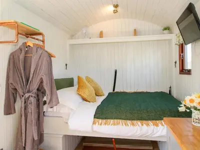 a small bedroom with a bed and a desk at Balwen Shepherd's Hut in Montgomery