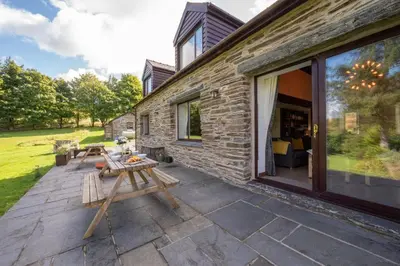 a patio with a wooden picnic table next to a building at 4 Bed in Ffestiniog oc-bow172 in Ffestiniog