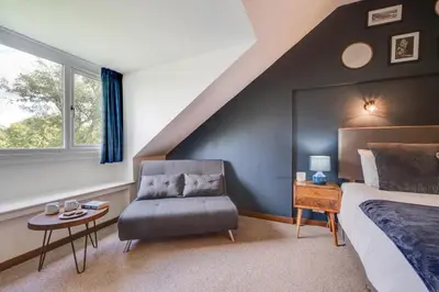 a bedroom with a bed and a chair and a window at 4 Bed in Ffestiniog oc-bow172 in Ffestiniog