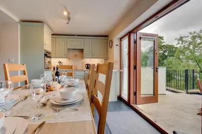 a kitchen and dining room with a table with wine glasses at 4 Bed in Llanarmon Dyffryn Ceiriog oc-bow152 in Llanarmon Dyffryn-Ceiriog