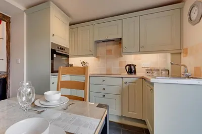 a kitchen with white cabinets and a table at 4 Bed in Llanarmon Dyffryn Ceiriog oc-bow152 in Llanarmon Dyffryn-Ceiriog