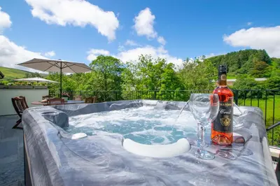 a bottle of wine and a glass in a hot tub at 4 Bed in Llanarmon Dyffryn Ceiriog oc-bow152 in Llanarmon Dyffryn-Ceiriog