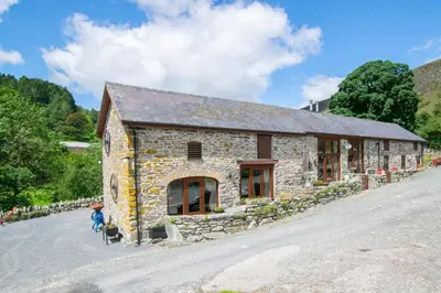 a stone building on a hill with a person standing in front of it at 4 Bed in Llanarmon Dyffryn Ceiriog oc-bow151 in Llanarmon Dyffryn-Ceiriog