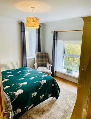 a bedroom with a bed and a chair and a window at Gorwel, Spacious 3 Bedroom Cottage near the Beach in Llanarth