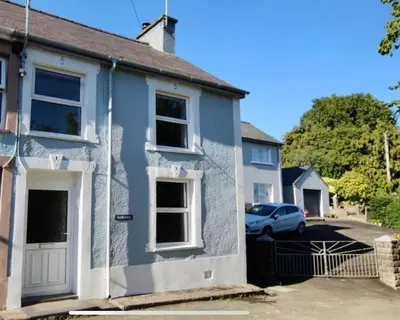 a blue house with a car parked in the driveway at Gorwel, Spacious 3 Bedroom Cottage near the Beach in Llanarth