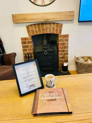 a book sitting on a table with a cup of coffee at Gorwel, Spacious 3 Bedroom Cottage near the Beach in Llanarth