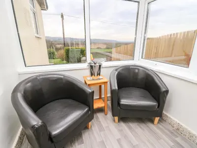 two black leather chairs in a room with windows at Gwynant in Ystrad Meurig
