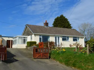 a white house with a gate in front of it at Gwynant in Ystrad Meurig